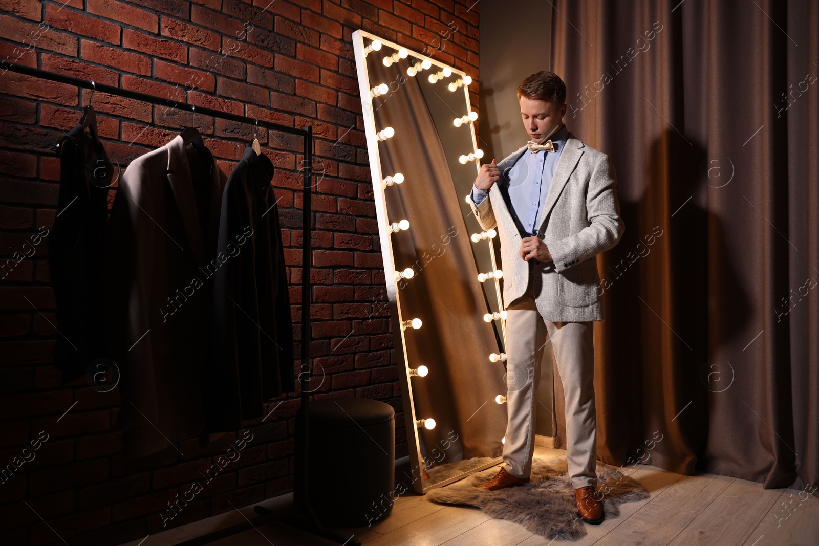 Handsome man getting ready near mirror indoors Photo of Handsome man getting ready near mirror indoors