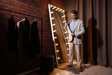 Photo of Handsome man getting ready near mirror indoors