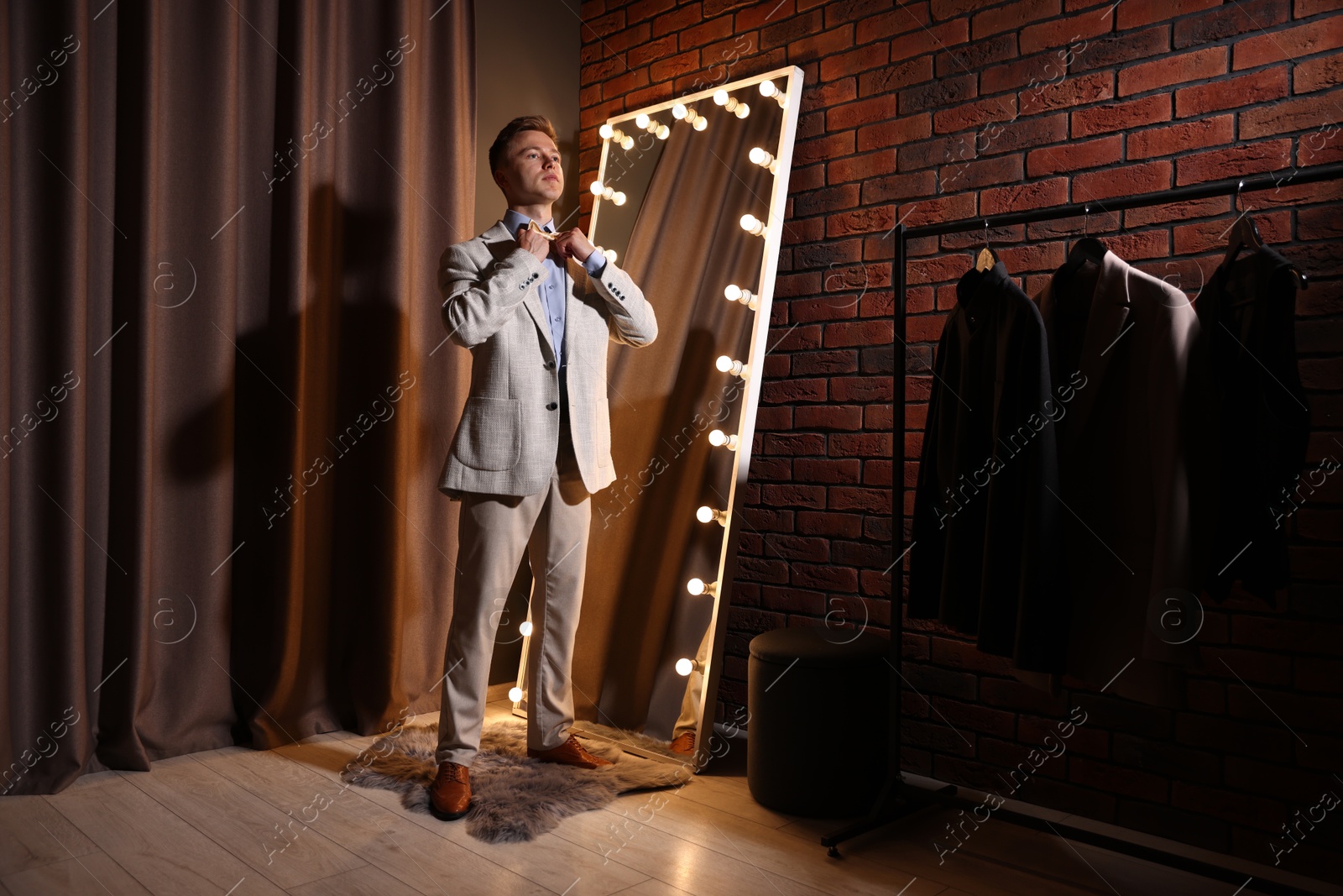 Handsome man getting ready near mirror indoors Photo of Handsome man getting ready near mirror indoors