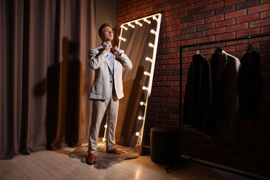 Photo of Handsome man getting ready near mirror indoors