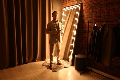 Photo of Handsome man getting ready near mirror indoors