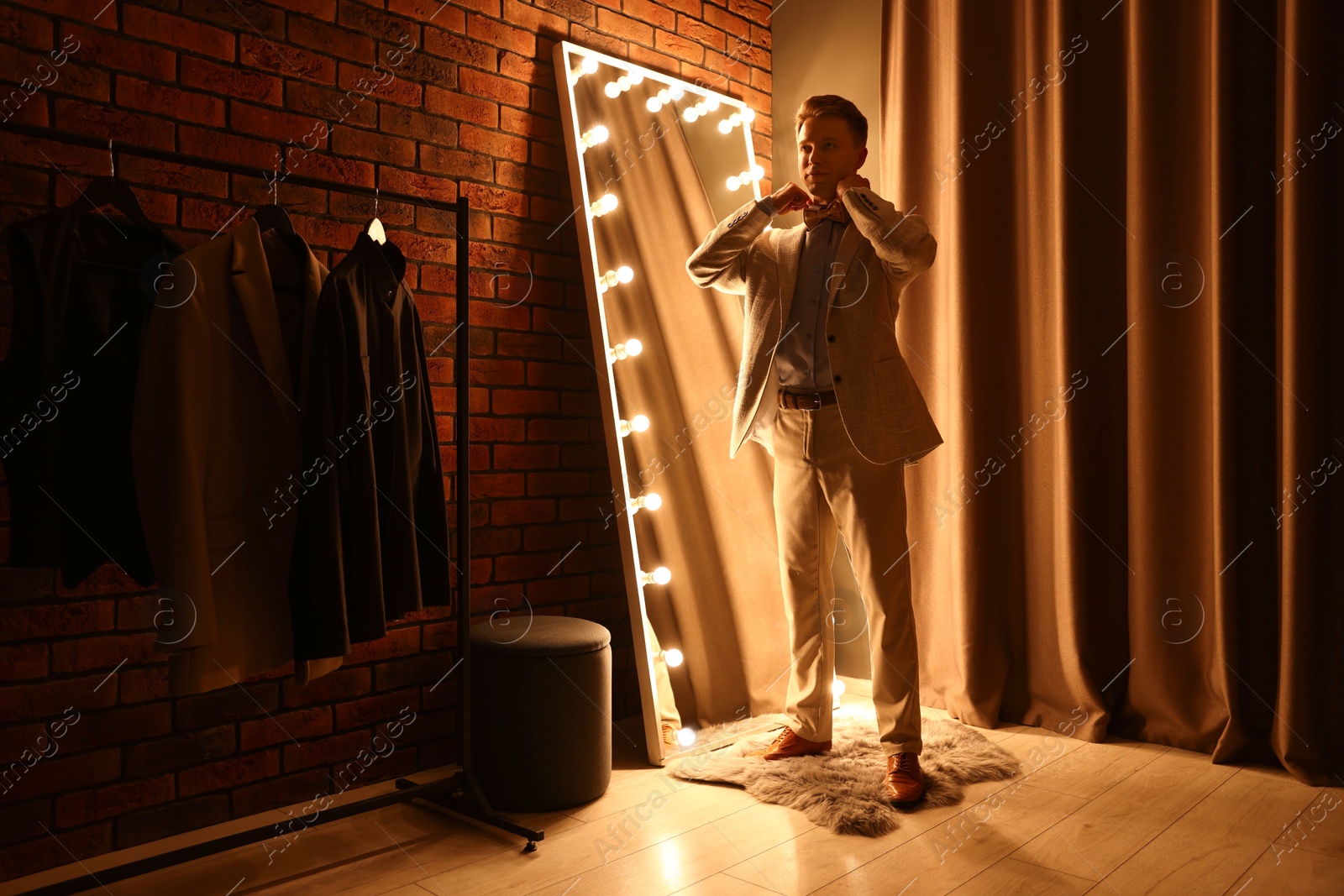Handsome man getting ready near mirror indoors Photo of Handsome man getting ready near mirror indoors
