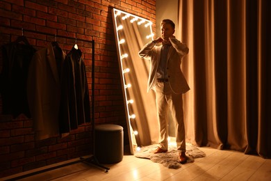 Photo of Handsome man getting ready near mirror indoors