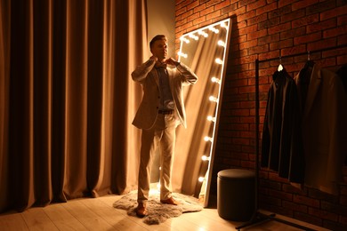 Photo of Handsome man getting ready near mirror indoors