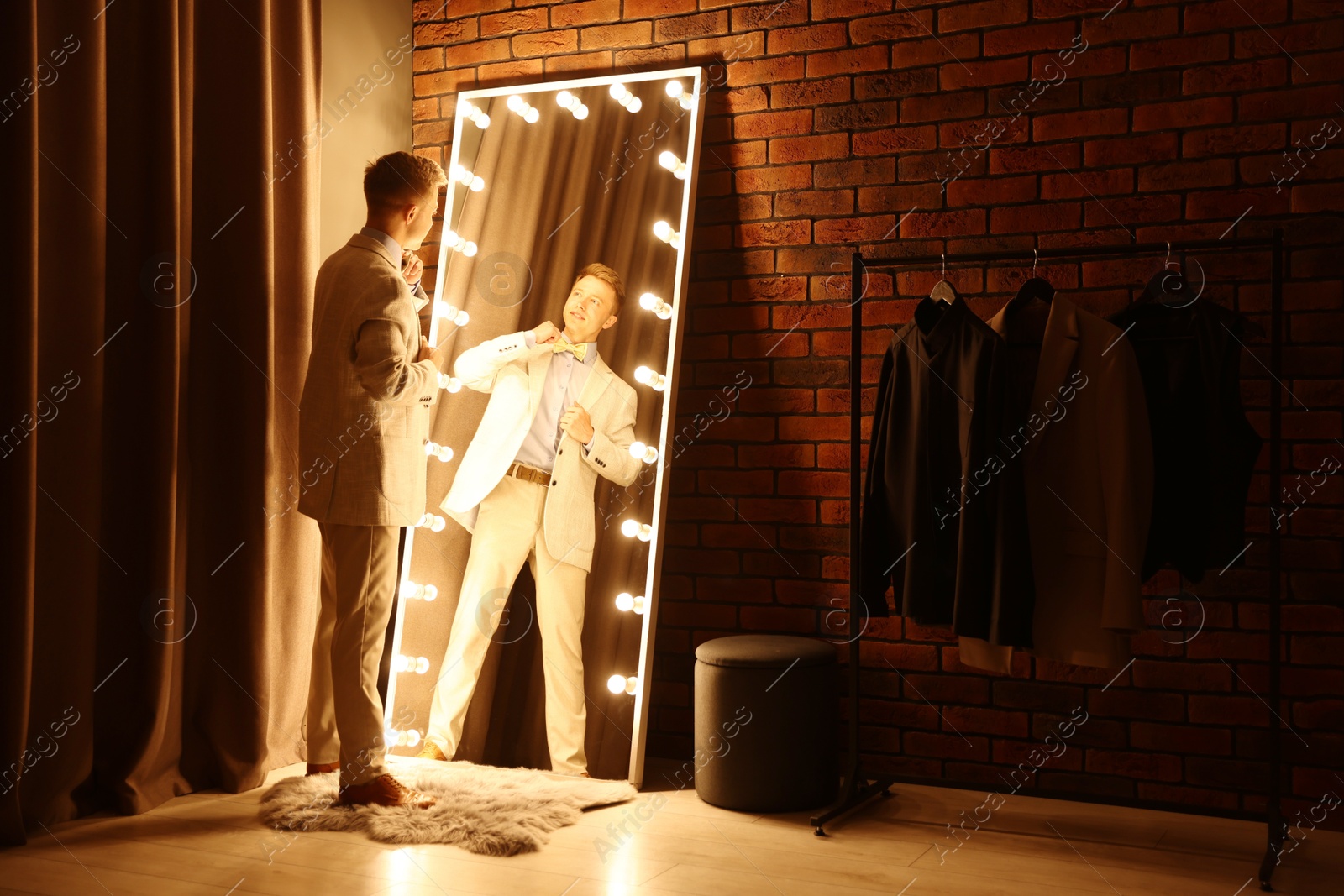 Handsome man getting ready near mirror indoors Photo of Handsome man getting ready near mirror indoors