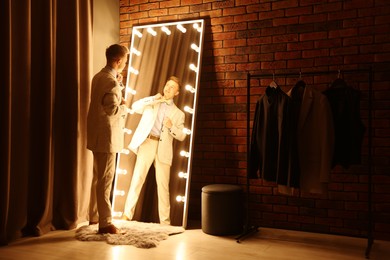 Photo of Handsome man getting ready near mirror indoors