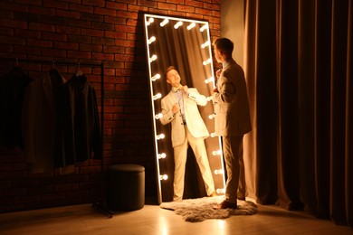 Photo of Handsome man getting ready near mirror indoors