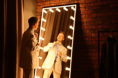 Photo of Handsome man getting ready near mirror indoors