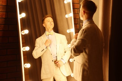 Photo of Handsome man getting ready near mirror indoors