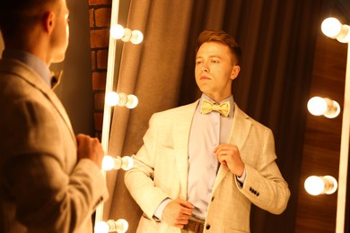 Photo of Handsome man getting ready near mirror indoors