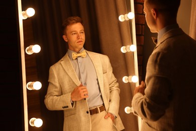 Photo of Handsome man getting ready near mirror indoors