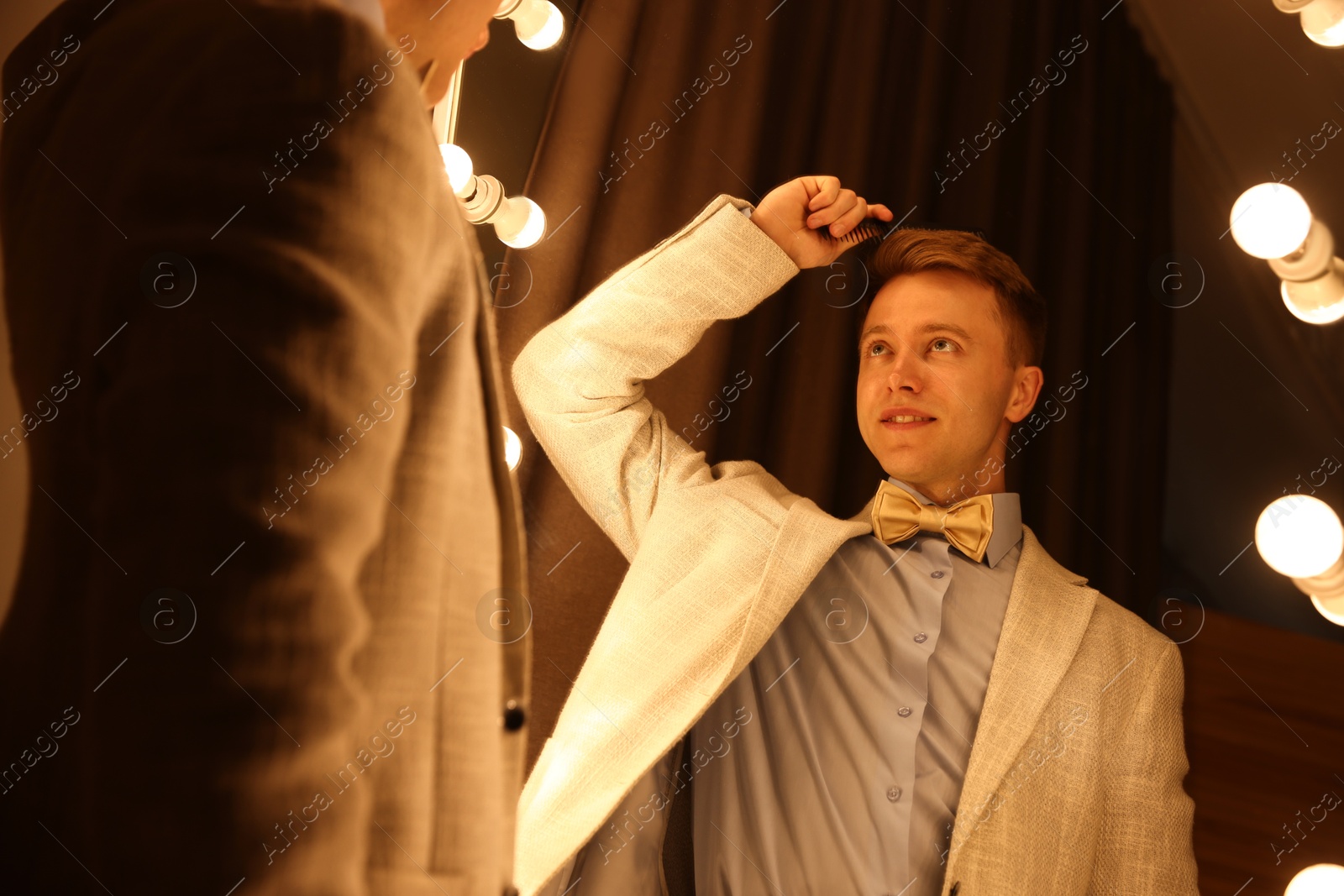Handsome man brushing his hair while getting ready near mirror indoors Photo of Handsome man brushing his hair while getting ready near mirror indoors