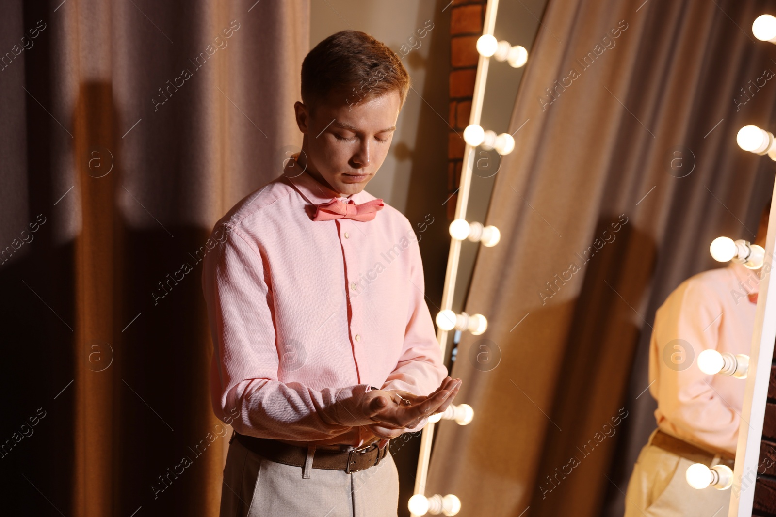 Man with cufflinks getting ready near mirror indoors Photo of Man with cufflinks getting ready near mirror indoors