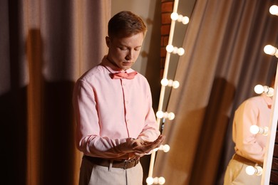 Photo of Man with cufflinks getting ready near mirror indoors