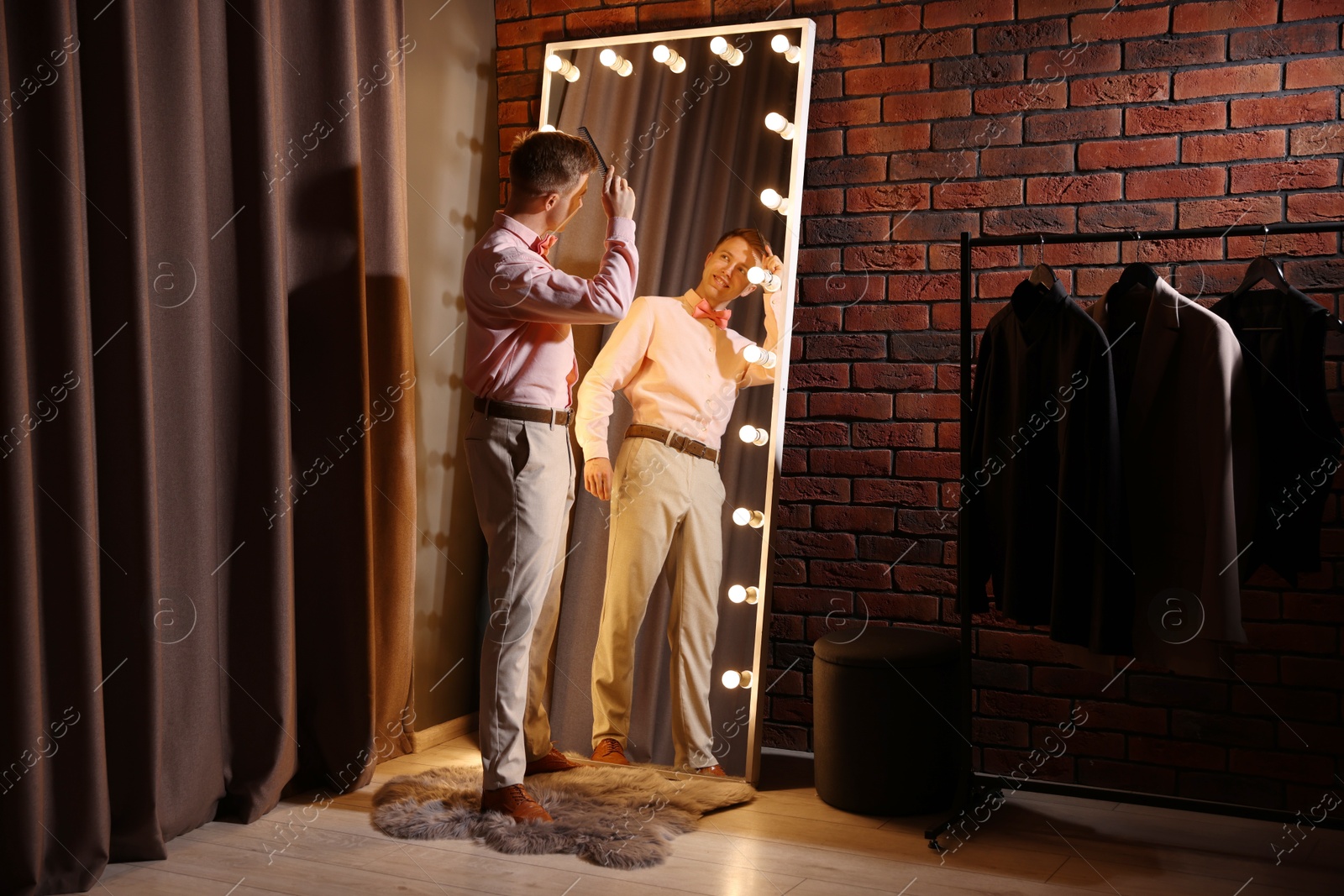 Handsome man brushing his hair while getting ready near mirror indoors Photo of Handsome man brushing his hair while getting ready near mirror indoors