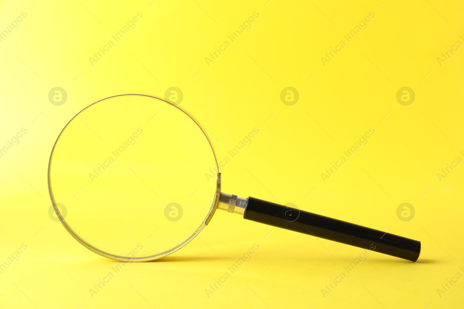 Magnifying glass with handle on yellow background Photo of Magnifying glass with handle on yellow background