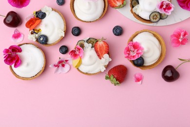 Photo of Delicious dessert. Tartlets with cream, berries and flowers on pink background, flat lay. Space for text