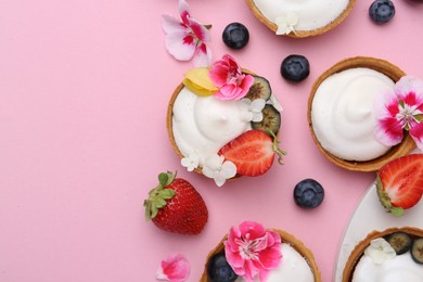Photo of Delicious dessert. Tartlets with cream, berries and flowers on pink background, flat lay. Space for text