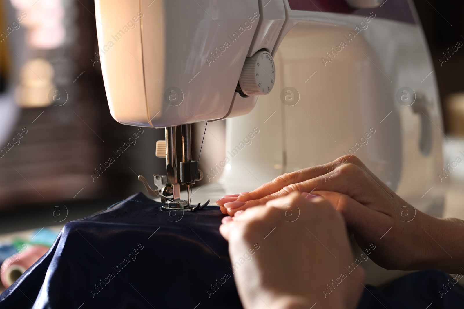 Woman working with sewing machine in workshop, closeup Photo of Woman working with sewing machine in workshop, closeup