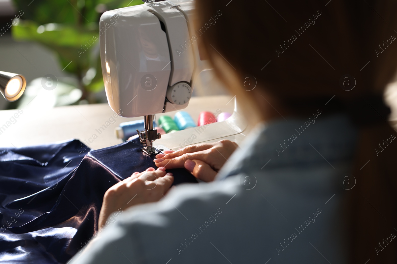 Woman working with sewing machine in workshop, closeup Photo of Woman working with sewing machine in workshop, closeup