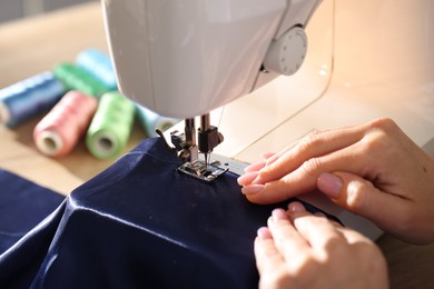 Photo of Woman working with sewing machine at table, closeup