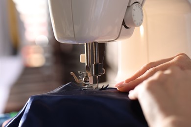 Photo of Woman working with sewing machine on blurred background, macro view