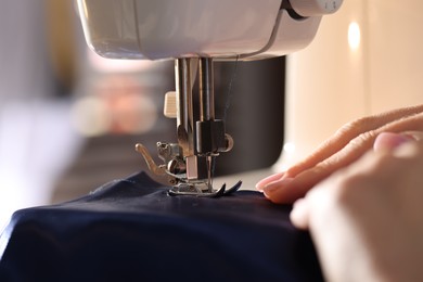 Photo of Woman working with sewing machine on blurred background, macro view