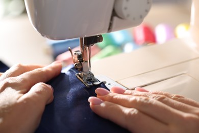 Photo of Woman working with sewing machine on blurred background, macro view