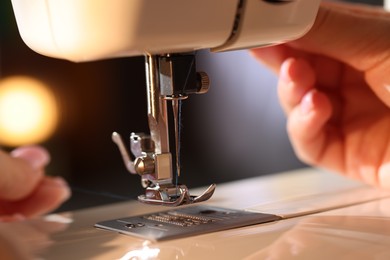 Photo of Woman threading sewing machine needle on blurred grey background, macro view