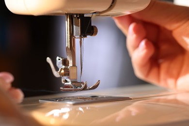 Photo of Woman threading sewing machine needle on blurred grey background, macro view