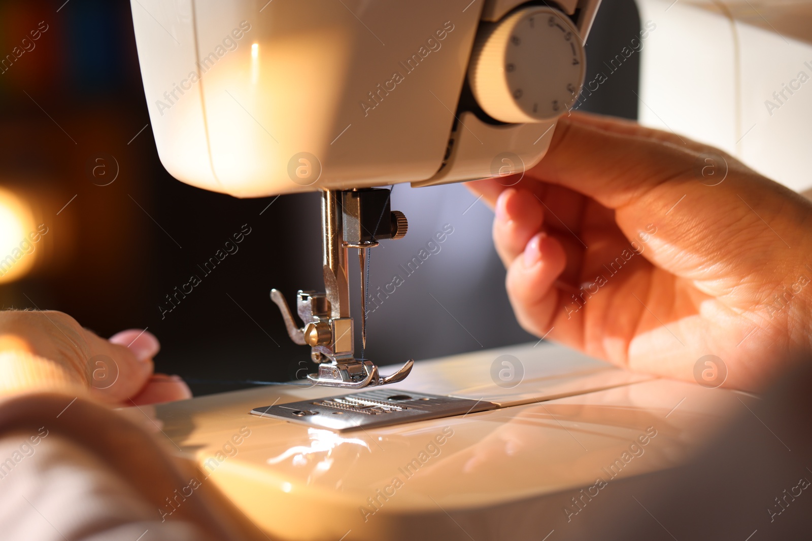 Woman threading sewing machine needle on blurred background, macro view Photo of Woman threading sewing machine needle on blurred background, macro view