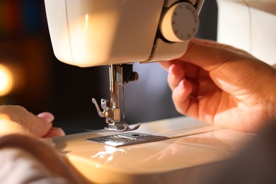 Photo of Woman threading sewing machine needle on blurred background, macro view