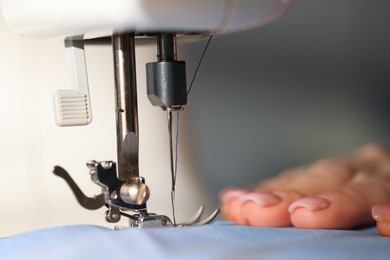 Photo of Woman working with sewing machine on blurred grey background, macro view