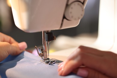 Photo of Woman working with sewing machine on blurred grey background, macro view