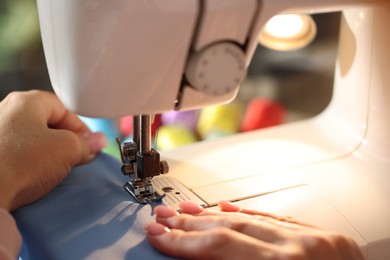 Photo of Woman working with sewing machine on blurred background, macro view