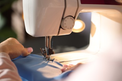Photo of Woman working with sewing machine on blurred background, macro view