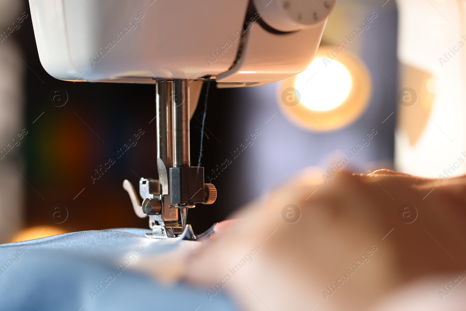 Woman working with sewing machine on blurred background, macro view Photo of Woman working with sewing machine on blurred background, macro view