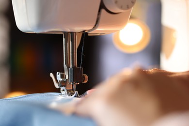 Photo of Woman working with sewing machine on blurred background, macro view