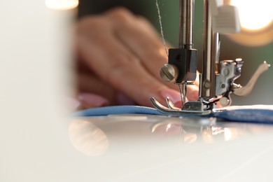 Photo of Woman working with sewing machine on blurred background, macro view