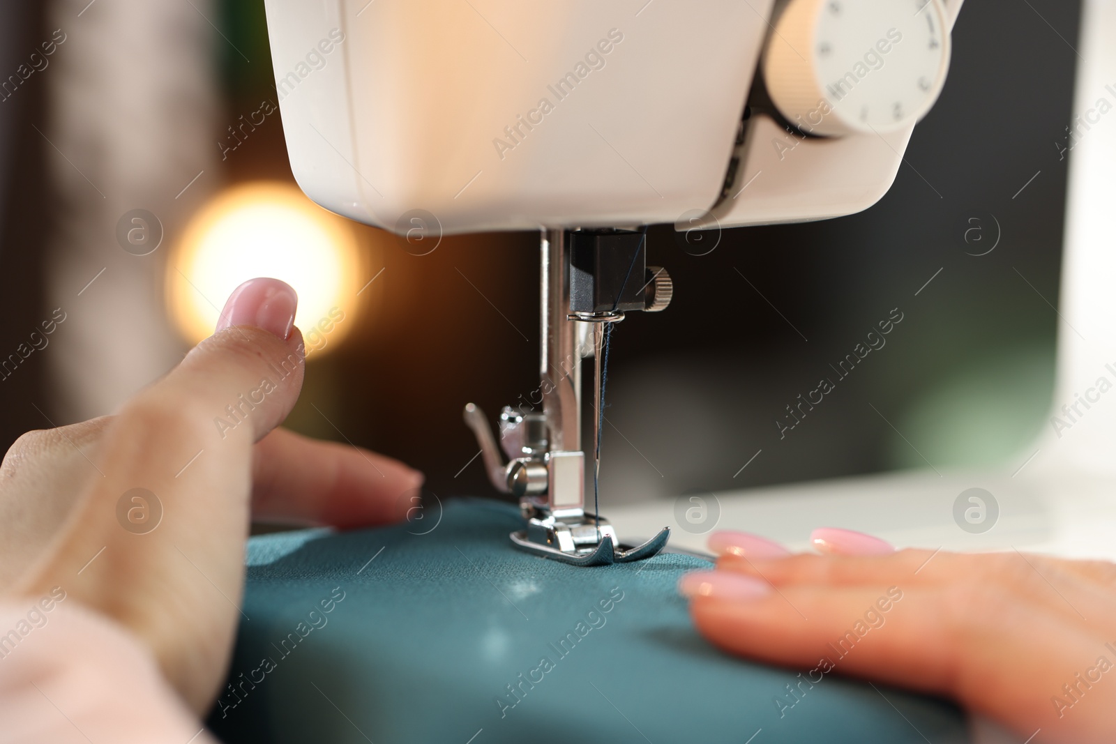 Woman working with sewing machine on blurred background, macro view Photo of Woman working with sewing machine on blurred background, macro view