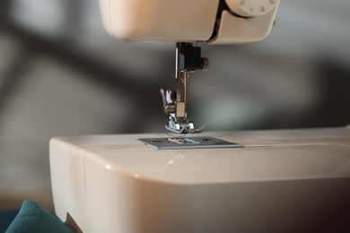 Photo of Sewing machine with thread on blurred grey background, macro view