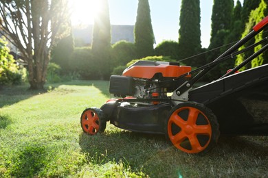 Photo of One lawn mower on green grass in garden, closeup. Space for text