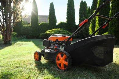 Photo of One lawn mower on green grass in garden, closeup. Space for text