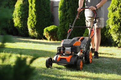 Photo of Man cutting green grass with lawn mower in garden, closeup. Space for text
