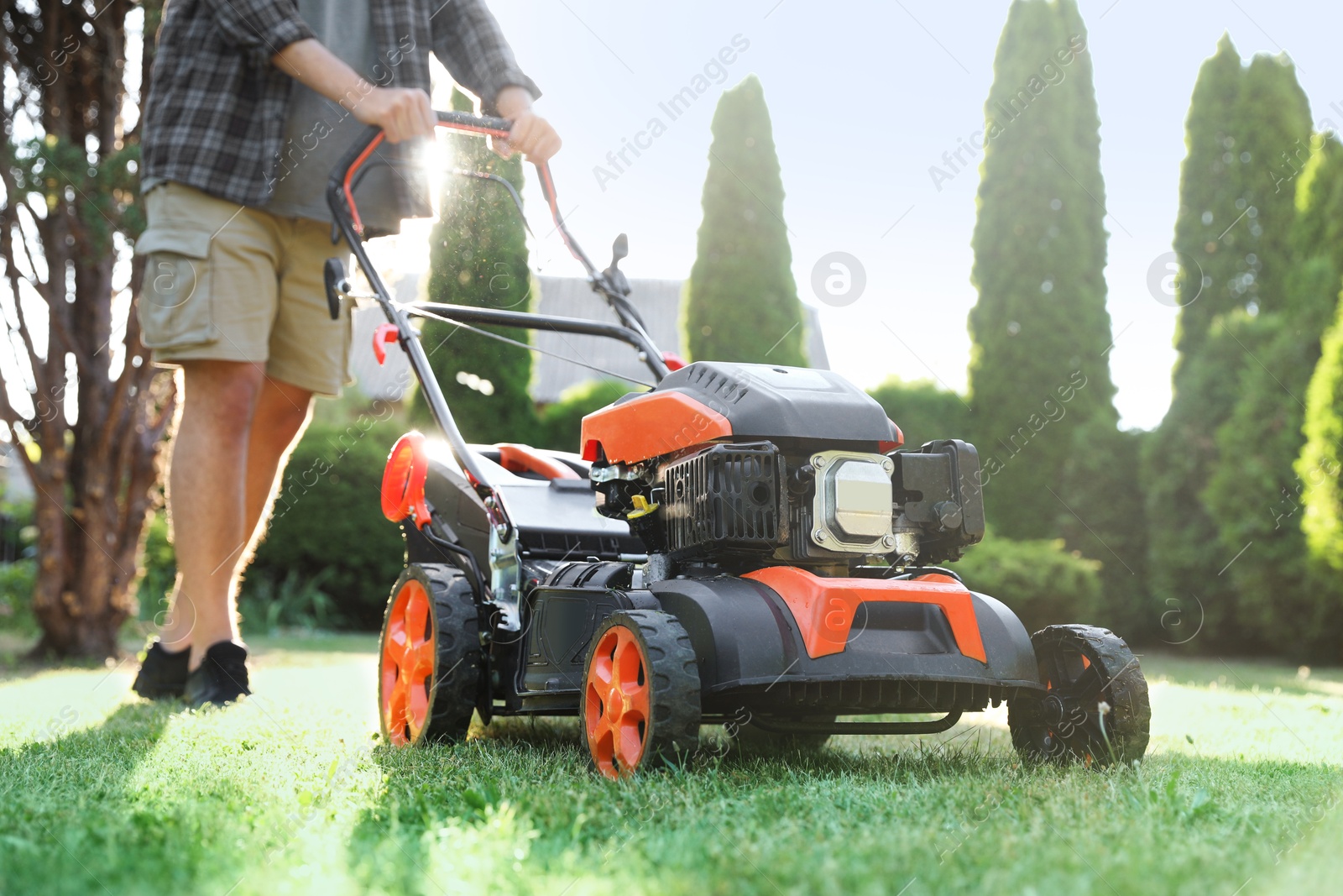 Man cutting green grass with lawn mower in garden, closeup Photo of Man cutting green grass with lawn mower in garden, closeup