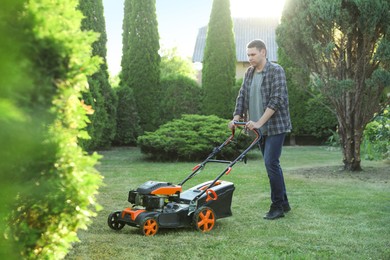 Photo of Man cutting green grass with lawn mower in garden