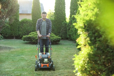 Photo of Man cutting green grass with lawn mower in garden