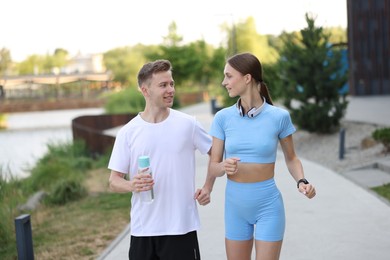 Photo of Happy couple with bottle of water running outdoors. Morning exercise