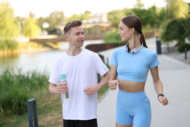 Photo of Happy couple with bottle of water running outdoors. Morning exercise