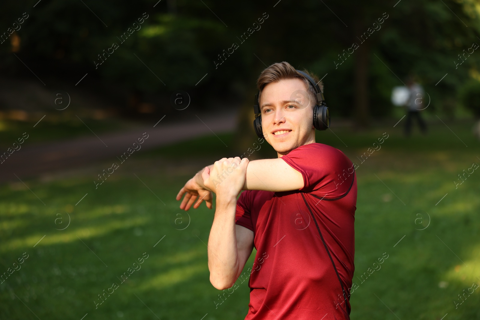 Smiling sportsman in headphones doing morning exercise outdoors Photo of Smiling sportsman in headphones doing morning exercise outdoors